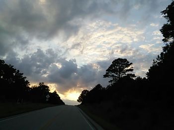 Road passing through landscape against cloudy sky