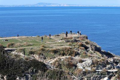 High angle view of people on cliff against sea