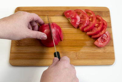 Cropped image of hands cutting tomatoes