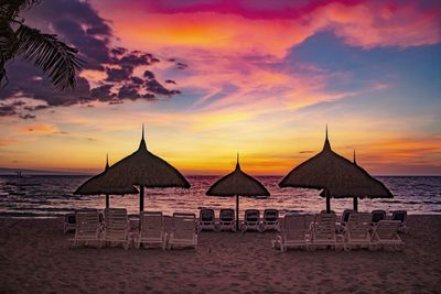 Built structure on beach against sky during sunset