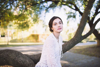 Portrait of young woman against tree