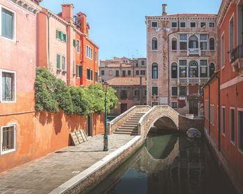 Arch bridge over canal amidst buildings in city