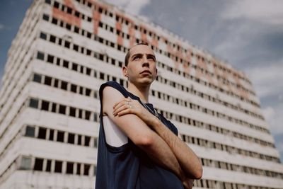 Low angle view of man standing against building and sky in city 