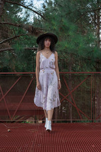 Full length portrait of woman standing against plants