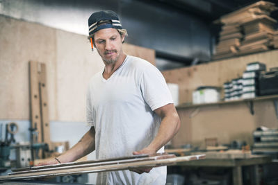 Carpenter looking at wooden planks in workshop