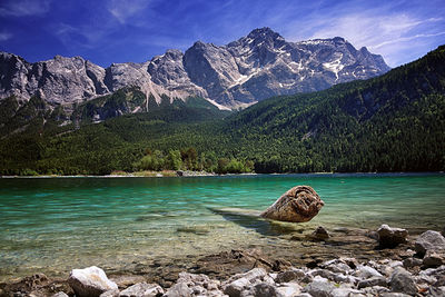 Scenic view of lake by rocky mountains against sky