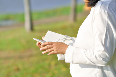 Midsection of man using mobile phone on field