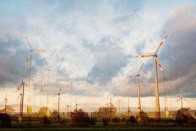 Wind turbines on field against sky