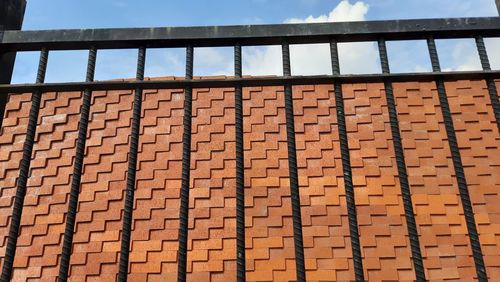 Low angle view of brick wall by building against sky