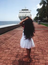 Girl standing on promenade against cruise ship moored in sea