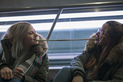 Female friends eating food while sitting on escalator