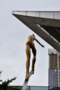 Low angle view of shirtless man sculpture against sky