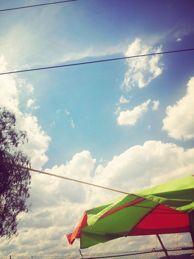 low angle view, sky, cloud, cloud - sky, cable, blue, hanging, power line, multi colored, flag, day, outdoors, cloudy, identity, no people, patriotism, built structure, pole, architecture, sunlight