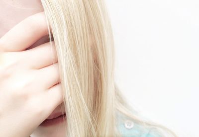 Close-up of worried girl covering her face against white background