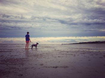 Rear view of men on beach against sky