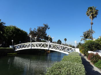 Arch bridge over river against clear blue sky