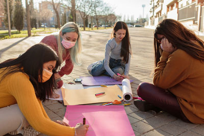 Females wearing mask writing on banners