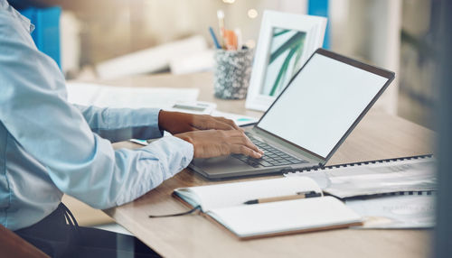 Midsection of man using laptop at office