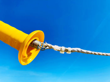 Low angle view of yellow chain against blue sky