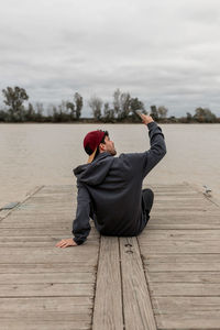 Side view of man using mobile phone while sitting on wood