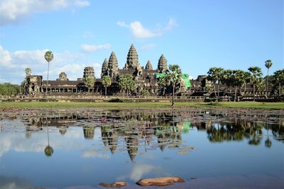 Angkor wat temple by lake against blue sky