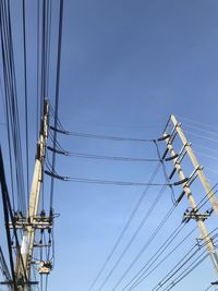 Low angle view of electricity pylon against blue sky