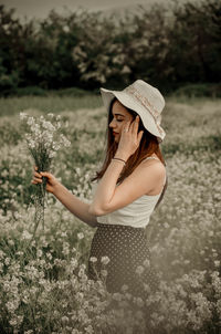 Woman wearing hat standing on field