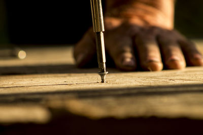 Close-up of man screwing nail in wood