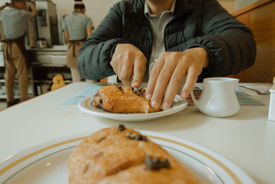 Midsection of man cutting food at table