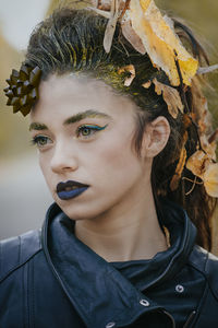 Close-up of young woman looking away while standing outdoors during autumn