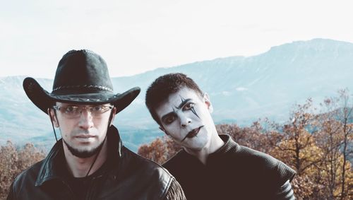 Portrait of young man standing with friend on mountain