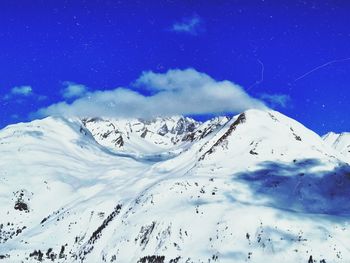 Scenic view of snowcapped mountains against blue sky