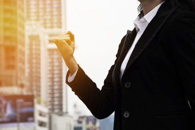 Midsection of businesswoman with clenched fist against building in city