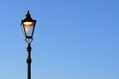 Low angle view of illuminated street light against clear blue sky