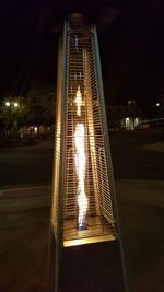 Illuminated lighting equipment in city against sky at night