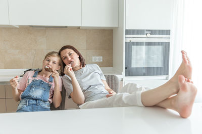 Young woman using mobile phone while sitting on bed at home