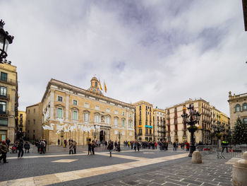 Group of people walking on street against buildings