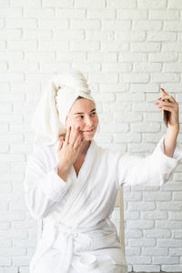 Happy young woman against white wall