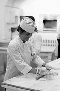 Happy chef rolling dough at counter