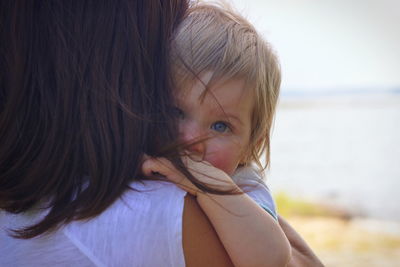 Rear view of mother carrying cute daughter while standing outdoors