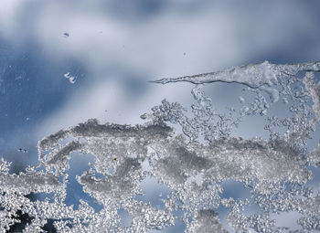 Close-up of frozen glass against sky