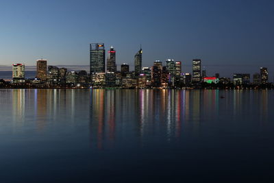 Illuminated buildings in city against clear sky