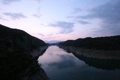 Scenic view of river amidst mountains against sky at dusk