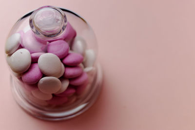 High angle view of pills spilling from bottle against pink background