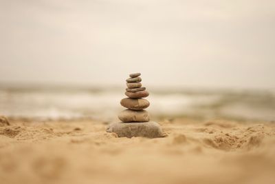 Stack of pebbles on beach against sky