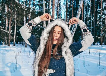 Woman with eyes closed standing in forest during winter