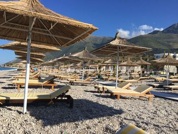 Lounge chairs and thatched roofs against sky