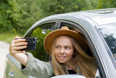 Portrait of young woman using mobile phone while sitting in car