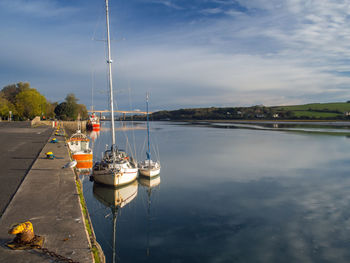 Sailboats moored at harbor against sky