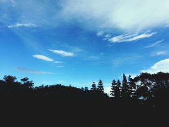 Low angle view of trees against cloudy sky